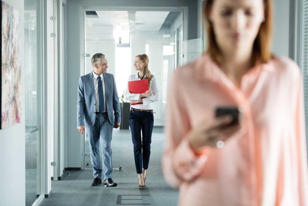 Coworkers talking and using mobile device